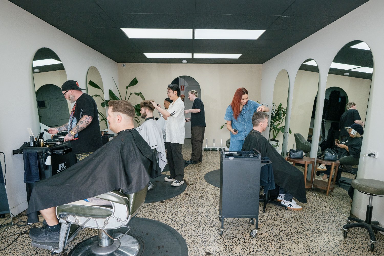 Barbers working under arched mirrors at Attaboy Barbers Hilton, Adelaide